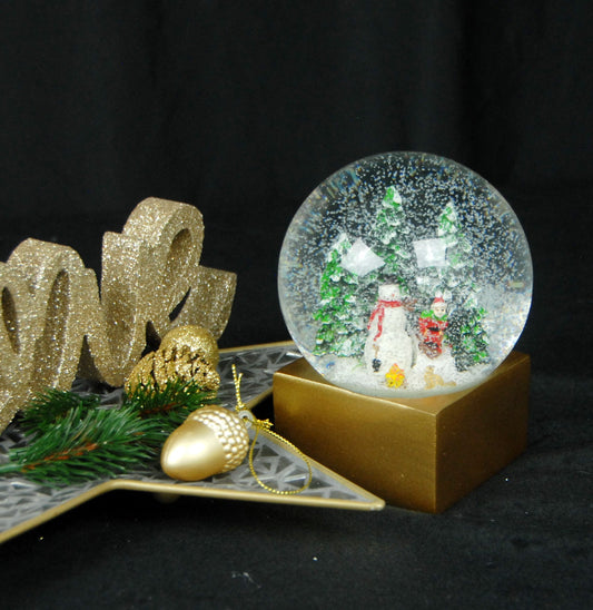 Schneekugel Schneemann steht vor Lagerfeuer auf Sockel golden eckig "PURE-Line" 10 cm Durchmesser - Schneekugelhaus