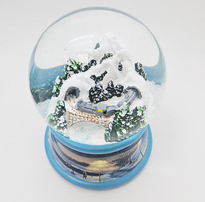 Nostalgische Schneekugel Berg mit Brücke Winterlandschaft blauer Rand 100 mm Durchmesser mit Spieluhr - Schneekugelhaus