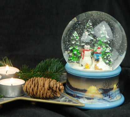 Schneekugel Schneemann steht im Winterwald mit Kind auf Schlitten auf Sockel Winterlandschaft Eisläufer blau mit Spieluhr - Schneekugelhaus